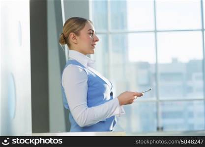 Attractive woman in office building. Young blond woman in modern glass interior using tablet