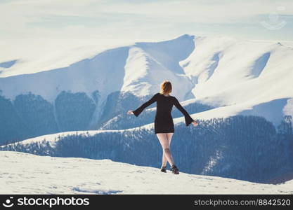Attractive woman in short dress on mountain scenic photography. Picture of person with snow capped peaks on background. High quality wallpaper. Photo concept for ads, travel blog, magazine, article. Attractive woman in short dress on mountain scenic photography