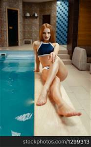Attractive woman in swimsuit lying at the pool indoors. Swimming and relaxation, healthy lifestyle, spa therapy. Woman in swimsuit lying at the pool indoors