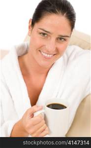 Attractive woman in white bathrobe with coffee in lounge