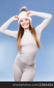 Attractive woman in winter cap and gray sports thermolinen underwear for skiing training studio shot on blue. Long sleeves top and leggings. woman in thermal underwear