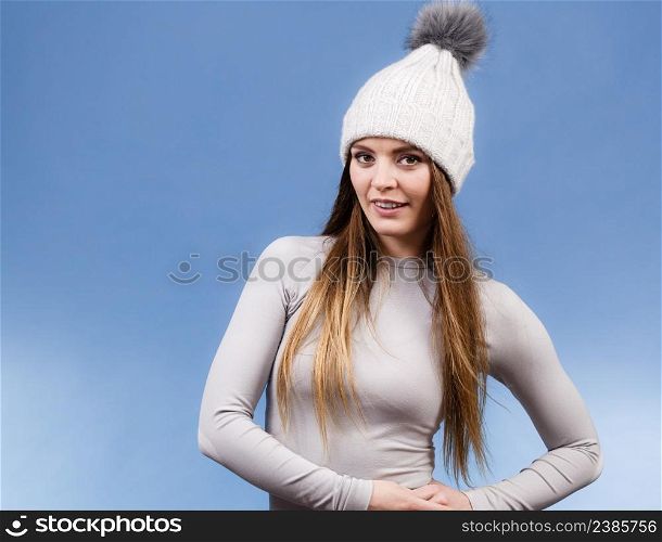 Attractive woman in winter cap and gray sports thermolinen underwear for skiing training studio shot on blue. Long sleeves top . woman in thermal underwear