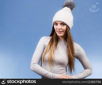 Attractive woman in winter cap and gray sports thermolinen underwear for skiing training studio shot on blue. Long sleeves top . woman in thermal underwear