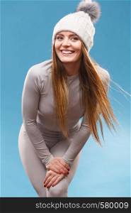 Attractive woman in winter cap and gray sports thermolinen underwear for skiing training studio shot on blue. Long sleeves top and leggings. woman in thermal underwear