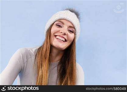 Attractive woman in winter cap and gray sports thermolinen underwear for skiing training studio shot on blue. Long sleeves top . woman in thermal underwear