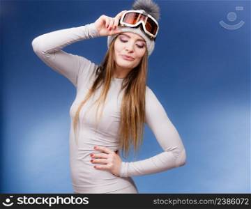 Attractive woman in winter cap gray sports thermal underwear for skiing training ski googles studio shot on blue. . woman in thermal underwear ski googles