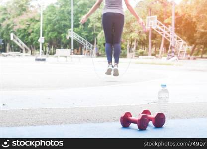 Attractive woman jumping with rope outdoor in the park, Healthy and wellness, Selective focus in foreground