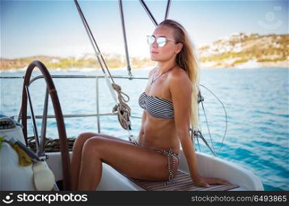 Attractive woman on sailboat, travels on a luxury yacht in Mediterranean sea along Greek islands, enjoying summer vacation. Attractive woman on sailboat