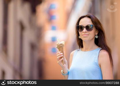 Attractive woman on the street having fun and eating ice cream. Young female model eating ice cream cone on summer day. Attractive woman on the street having fun and eating ice cream. Y