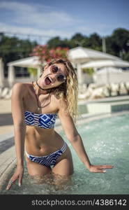 Attractive woman posing in the swimming pool wearing bikini