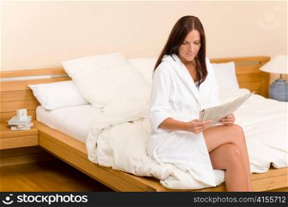 Attractive woman reading morning newspapers in bedroom wear bathrobe