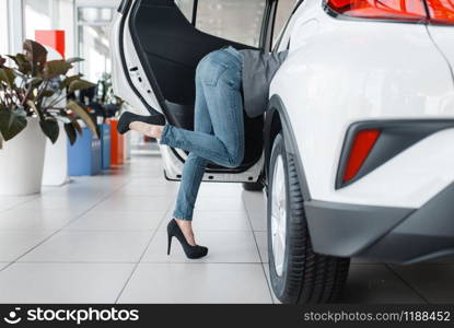 Attractive woman&rsquo;s ass sticking out of new car in showroom. Female customers choosing vehicle in dealership, automobile sale, auto purchase