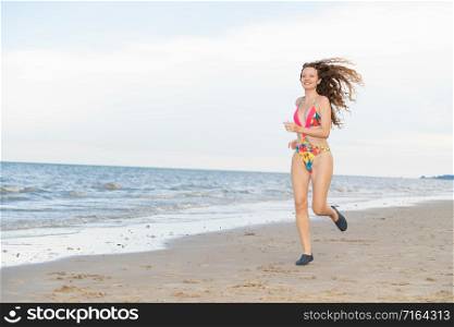 Attractive woman runner runs on tropical sand beach in summer. Healthy lifestyle and running sport concept.. Attractive woman runs on sand beach in summer.
