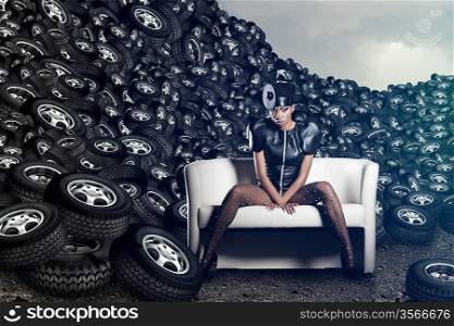Attractive woman siting in chair on tires on cloudy sky