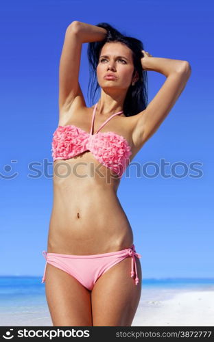 attractive woman sunbathing in pink bathing suit on beach