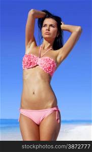 attractive woman sunbathing in pink bathing suit on beach