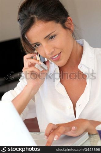 Attractive woman talking on mobile phone in front of laptop