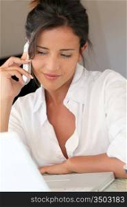 Attractive woman talking on mobile phone in front of laptop