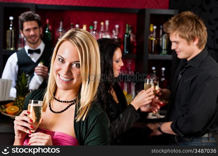 Attractive woman toast champagne with friends at cocktail bar