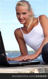 Attractive woman using her laptop on a pontoon