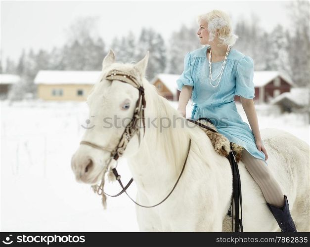 Attractive woman wearing blue dress and she riding a white horse