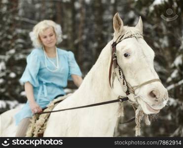 Attractive woman wearing blue dress and she riding a white horse, focus on horse eyes