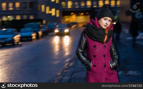Attractive woman wearing winter coat, city evening on background, focus on foreground