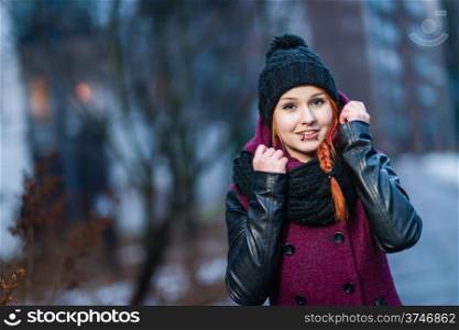 Attractive woman wearing winter coat, city evening on background, focus on foreground