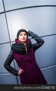 Attractive woman wearing winter coat, rounded wall on background