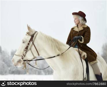 Attractive woman wearing winter jacket and hat, she riding a white horse