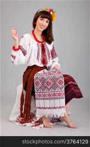 Attractive woman wears Ukrainian national dress is sewing isolated on a white background