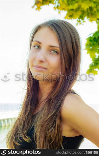 Attractive woman with dark long hair posing in summer clothing on sunny day with water in background. Attractive woman posing on sunny day