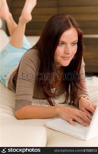 Attractive woman with laptop lying modern leather sofa living room