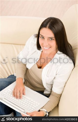 Attractive woman with laptop sitting on couch smiling