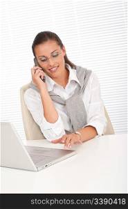 Attractive woman working with laptop holding phone