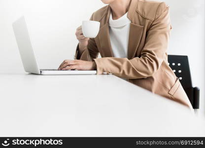 Attractive women in casual business sitting at a table working on her laptop computer at home office in front of a window