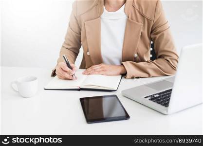 Attractive women in casual business sitting at a table working on her laptop computer at home office in front of a window