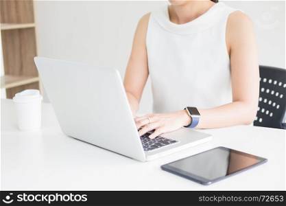 Attractive women in casual business sitting at a table working on her laptop computer at home office in front of a window