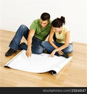 Attractive young adult couple looking at house plans.