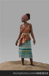 Attractive young African fashion model standing on sand on gray studio background