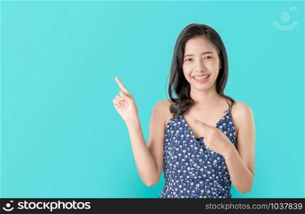 Attractive young Asian woman standing pointing finger, feeling happy on blue background.