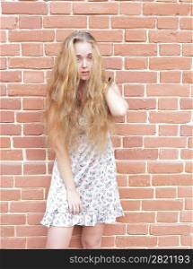 Attractive young blonde in wintage dress on the background of a brick wall.