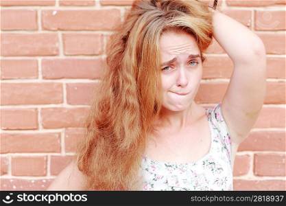 Attractive young blonde making a face on the background of a brick wall.