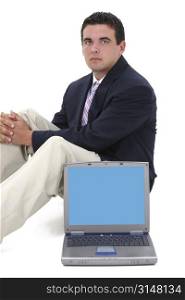 Attractive young business man in suit, sitting behind laptop computer over white background.
