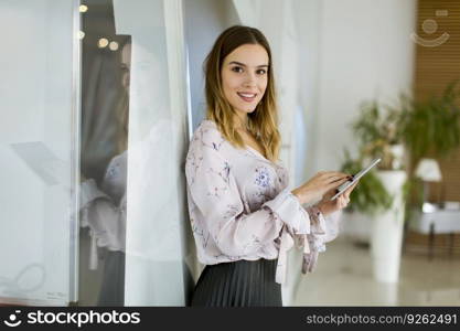 Attractive young businesswoman using a digital tablet while standing in the office