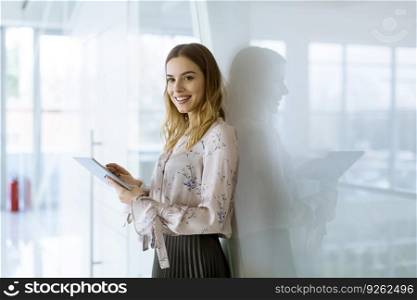Attractive young businesswoman using a digital tablet while standing in the office