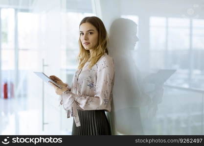 Attractive young businesswoman using a digital tablet while standing in the office