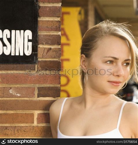 Attractive young Caucasian woman standing outside tattoo parlor.