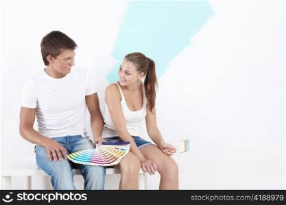 Attractive young couple chooses the color for painting walls