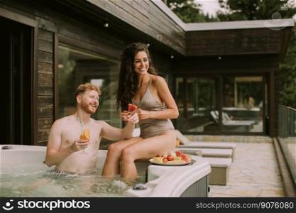 Attractive young couple enjoying in outdoor hot tub on vacation